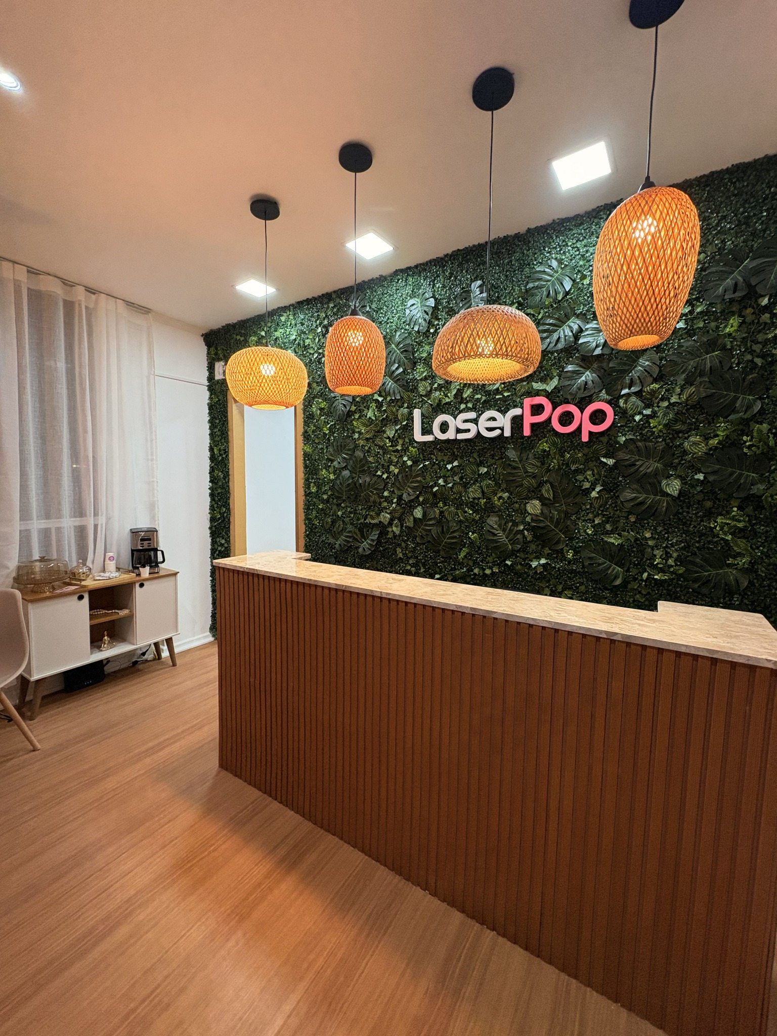 Recepção da Unidade Avenida Dom Pedro, com balcão de madeira, parede verde e logo Laser Pop